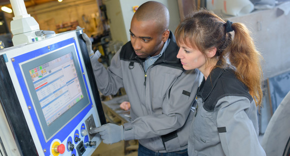 Eine Frau und ein Mann programmieren eine Maschine in der industriellen Fertigung