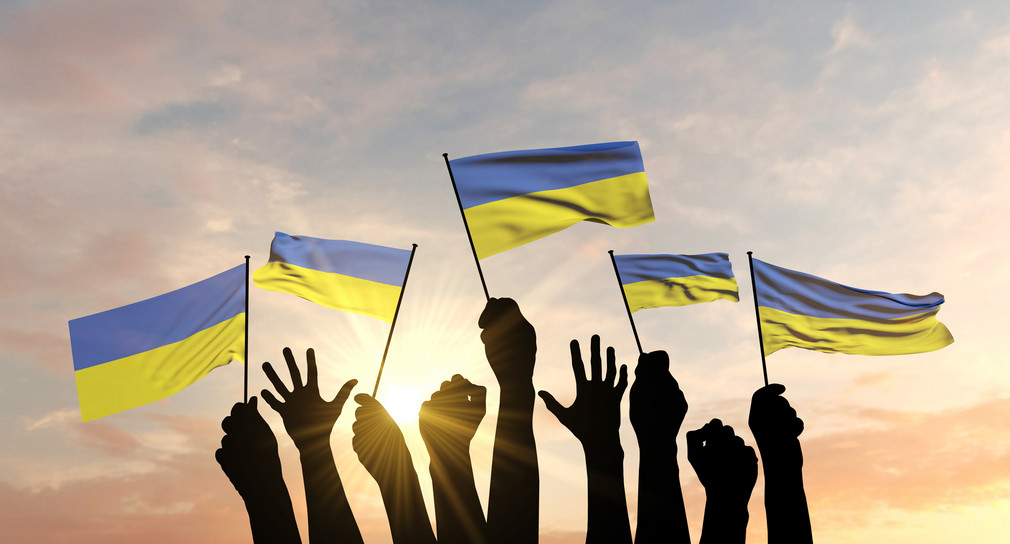 Silhouette von Armen, die Ukraine-Flaggen schwenken