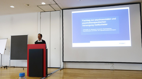 Fachtag Versorgung von traumatisierten Geflüchteten Dr. Alessandro Cavicchioli, Psychologischer Psychotherapeut, spricht vor Publikum in Veranstaltungssaal
