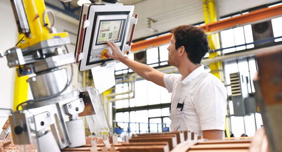 Junger Maschinenbauer steuert eine Maschine über einen Monitor (Bild: © industrieblick, stock.adobe)