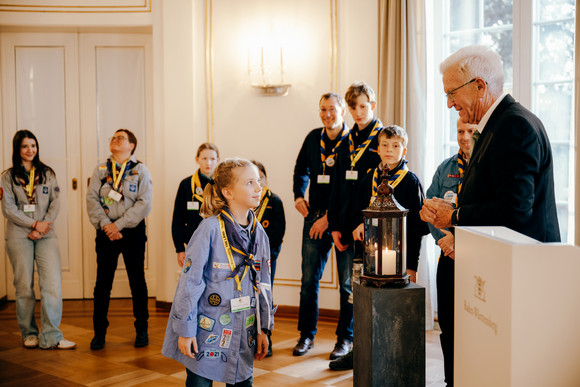 Ministerpräsident Winfried Kretschmann (rechts) mit Pfadfinderinnen und Pfadfindern bei der Übergabe des Friedenslichts