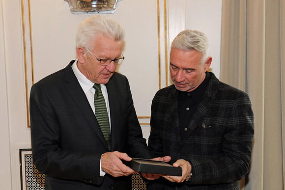 Film Kretschmann empfängt Filmemacher Roland Emmerich Ministerpräsident Winfried Kretschmann (l.) überreicht Roland Emmerich (r.) als Gastgeschenk einen Ammoniten aus Holzmaden.