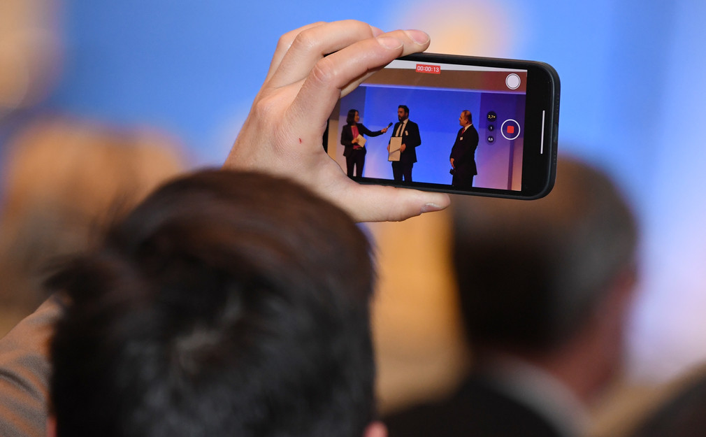 Ein Zuschauer fotografiert mit dem Handy die Preisverleihung.