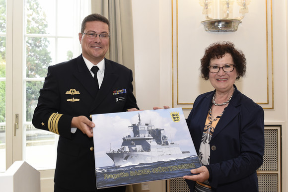 Empfang Besuch der Crew Alpha der Fregatte Baden-Württemberg Fregattenkapitän Markus Venker (l.) und Gerlinde Kretschmann (r.) mit einem Foto der Fregatte Baden-Württemberg