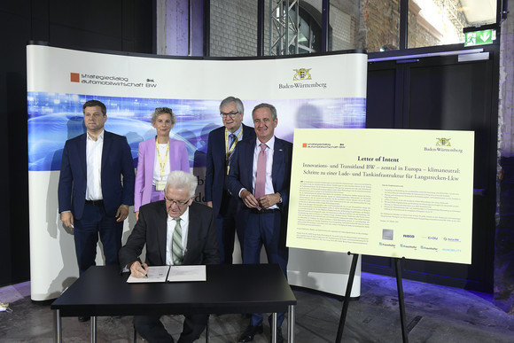 Top-Level-Meeting Fünfte Jahresveranstaltung des Strategiedialogs Automobilwirtschaft Ministerpräsident Winfried Kretschmann (vorne) unterzeichnet eine Absichtserklärung für ein „Pilot-Lade- und Wasserstoff-Tankinfrastrukturprojekt für Langstrecken-Lkw“.