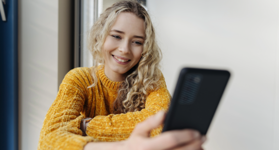 Junge blonde Frau mit Handy in der Hand.