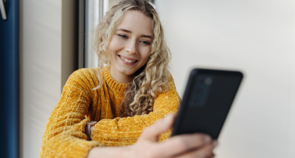 Junge blonde Frau mit Handy in der Hand.