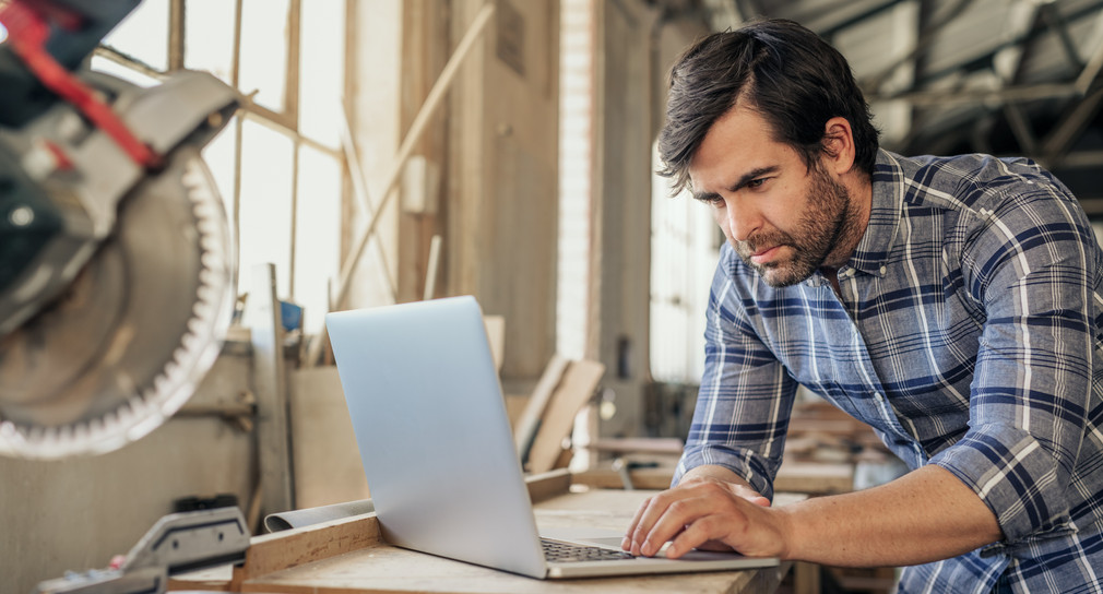 Woodworker doing research on a laptop in his workshop