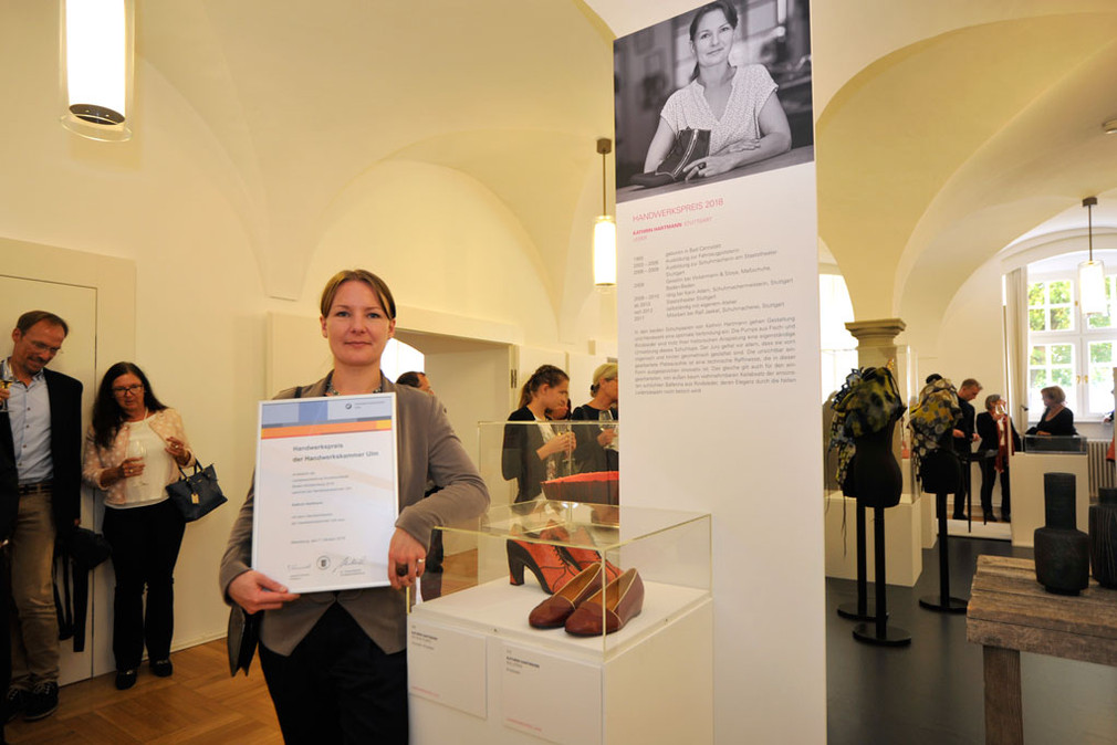 Die Handwerkspreisträgerin Kathrin Hartmann und ihre ausgezeichneten Schuhe in der Landesausstellung Kunsthandwerk.