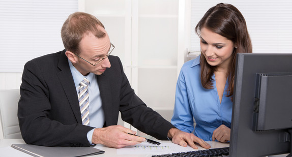 Eine Frau und ein Mann sitzen vor einem Monitor (Quelle: © Jeanette Dietl, Fotolia)