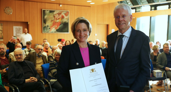 Auf dem Bild ist Ministerin Dr. Nicole-Hoffmeister-Kraut mit Herrn Dr. Andreas Zekorn zu sehen. Beide lächeln in die Kamera. Die Ministerin hält eine Urkunde in beiden Händen. 