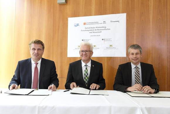 Mobilität Jahresveranstaltung Strategiedialog Automobilwirtschaft BW in Berlin Ministerpräsident Winfried Kretschmann (M.) sowie die Parlamentarischen Staatssekretäre Thomas Bareiß (l., Bundesministerium für Wirtschaft und Energie) und Steffen Bilger (r., Bundesministerium für Verkehr und digitale Infrastruktur) unterzeichnen eine Absichtserklärung zum Projekt HyFab, einer Forschungsfabrik für Brennstoffzellen und Wasserstoff (Bild: © e-mobil BW / Studio KD Busch)
