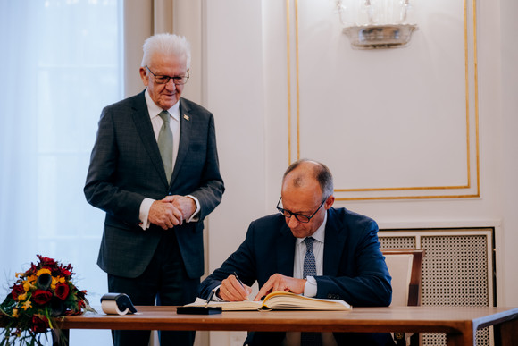 Antrittsbesuch Bundeskanzler Friedrich Merz besucht Baden-Württemberg Bundeskanzler Friedrich Merz (rechts) beim Eintrag in das Gästebuch des Landes, daneben steht Ministerpräsident Winfried Kretschmann (links)