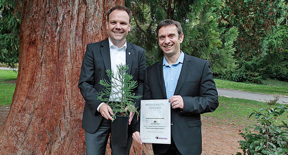 Der Direktor der Wilhelma, Dr. Thomas Kölpin, übergibt die Patenschaftsurkunde für den Mammutbaum an Staatssekretär Ingo Rust.