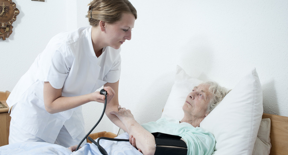 Eine Pflegerin misst bei einer Seniorin den Blutdruck