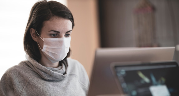 Frau mit Mund-Nasen-Schutz arbeitet in einem Büro