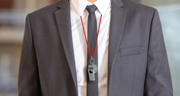 Mann in einem Anzug trägt eine Trillerpfeife um den Hals