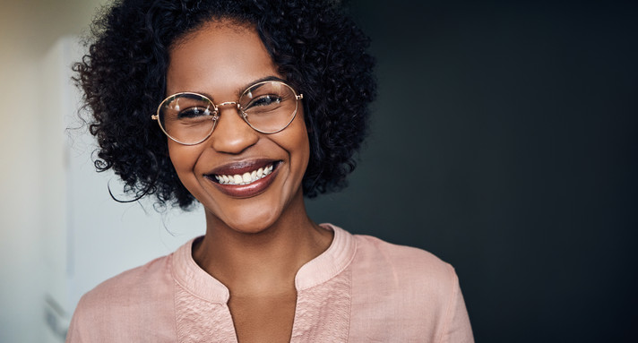 Confident young African businesswoman standing in an office laughing