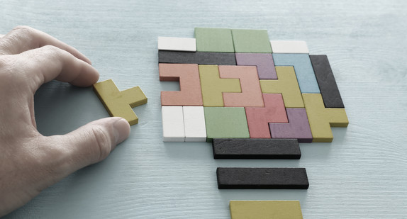 Eine Hand legt ein Holzpuzzle.