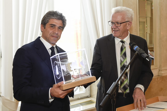 Europa Präsidentschaft der „Vier Motoren für Europa“ an die Lombardei übergeben Ministerpräsident Winfried Kretschmann (r.) übergibt Staatssekretär Alan Christian Rizzi (l.), Lombardei, einen Kubus (Bild: Staatsministerium Baden-Württemberg)