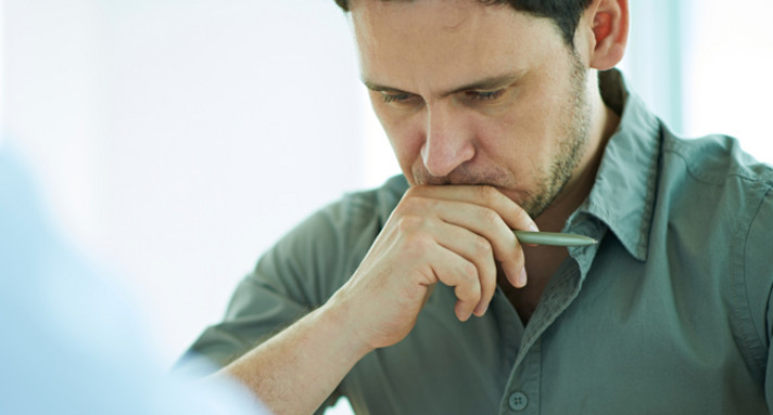 Ein Mann sitzt am Schreibtisch und überlegt (Foto: mediaphotos, iStock)