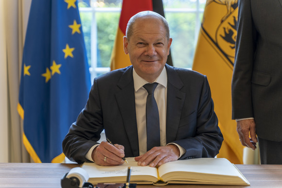 Bund-Länder-Beziehungen Bundeskanzler Olaf Scholz zu Besuch in Stuttgart Bundeskanzler Olaf Scholz sitzt im Runden Saal der Villa Reitzenstein in Stuttgart und trägt sich in das Gästebuch des Landes ein.
