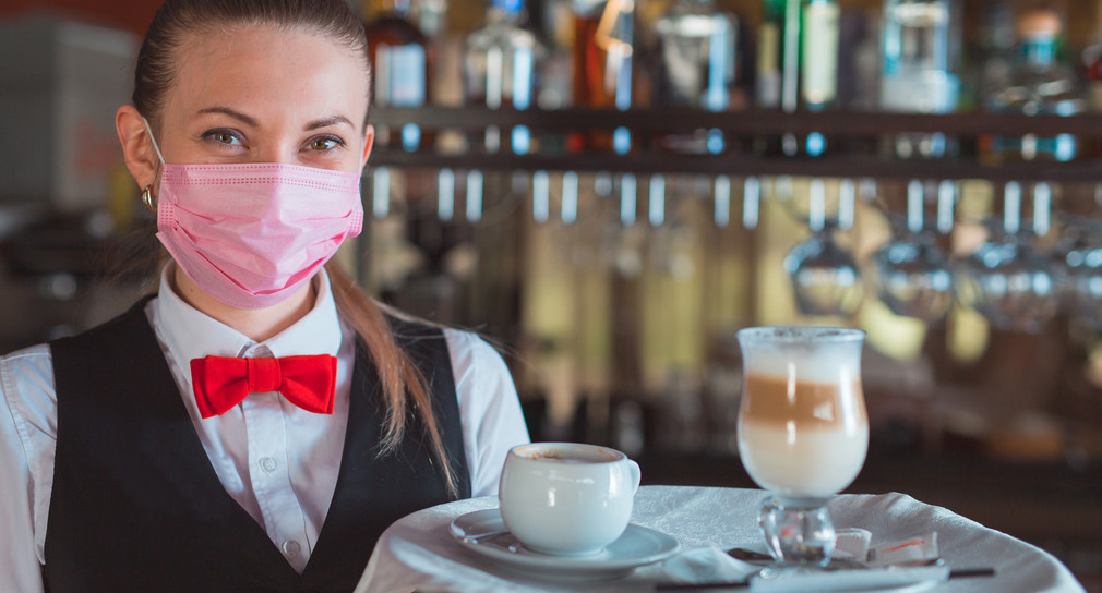 Servicekraft in einem Restaurant mit Mund-Nasen-Schutz