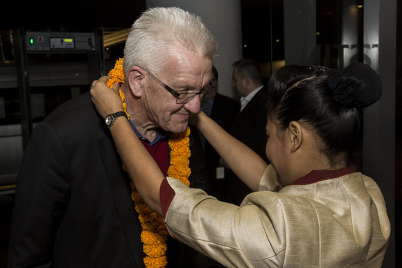 Delegationsreise Ministerpräsident Kretschmann besucht Indien Eine Frau hängt Ministerpräsident Winfried Kretschmann zur Begrüßung in einem Hotel in Pune eine Kette um.