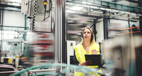 Industrial woman engineer with headset in a factory, working. Copy space.