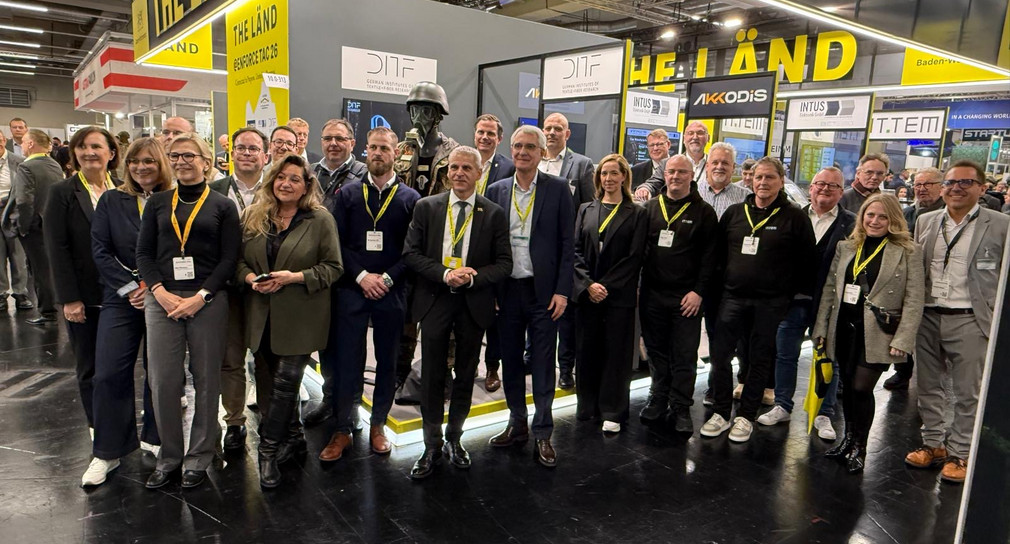 Gruppenbild mit mehreren Personen vor einem THE LÄND Messestand