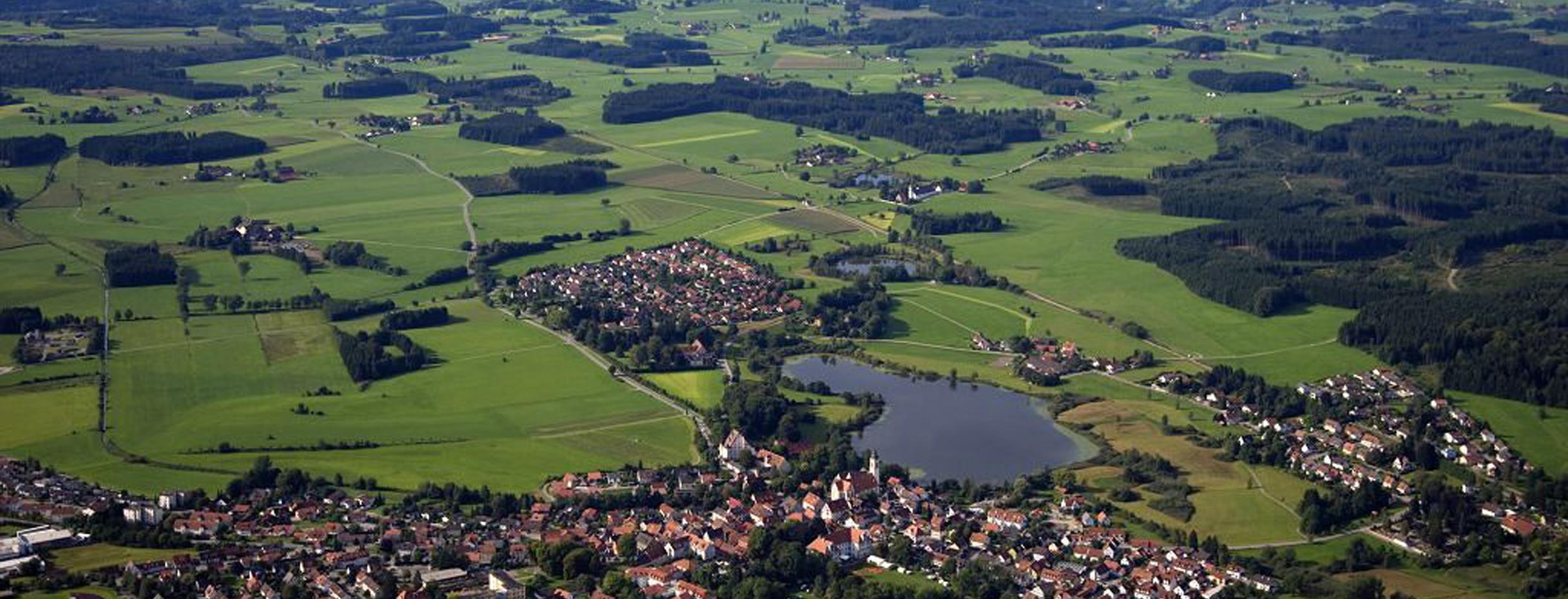 Luftaufnahme vom Allgäu: Kleine Stadt am See mit Feldern und Wiesen
