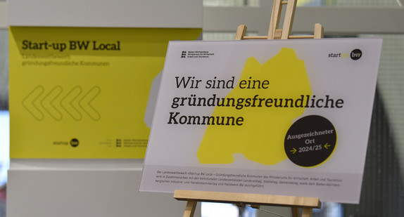 Staffelei mit einem Plakat, welches die Aufschrift "Wir sind eine gründungsfreundliche Kommune" hat