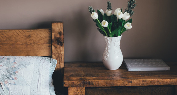 Hotelbett mit Tulpenstrauß auf dem Nachttisch