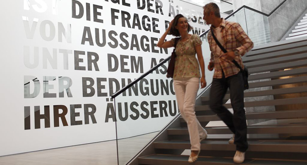 Ein Paar geht in einem Kunstmuseum eine Treppe hinunter