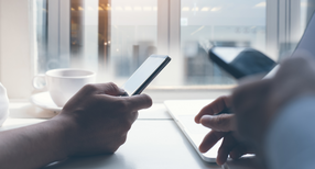 Zwei M&auml;nner sitzen an einem Tisch und nutzen Smartphones