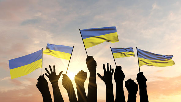 Silhouette von Armen, die Ukraine-Flaggen schwenken