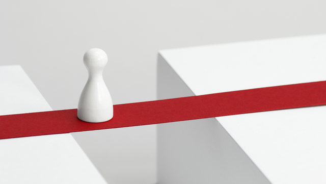 Symbolisches Bild: Ein wei&szlig;er Kegel steht auf einer roten Br&uuml;cke