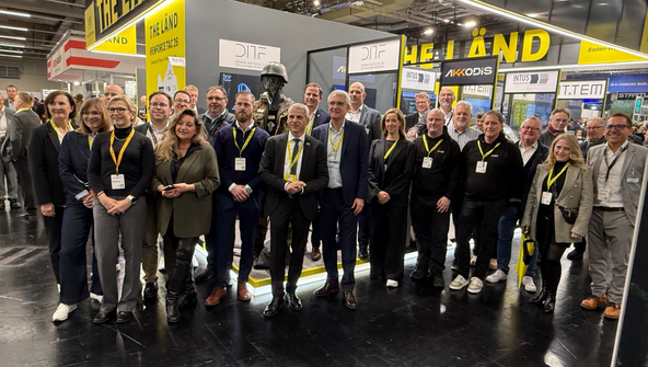 Gruppenbild mit mehreren Personen vor einem THE L&Auml;ND Messestand